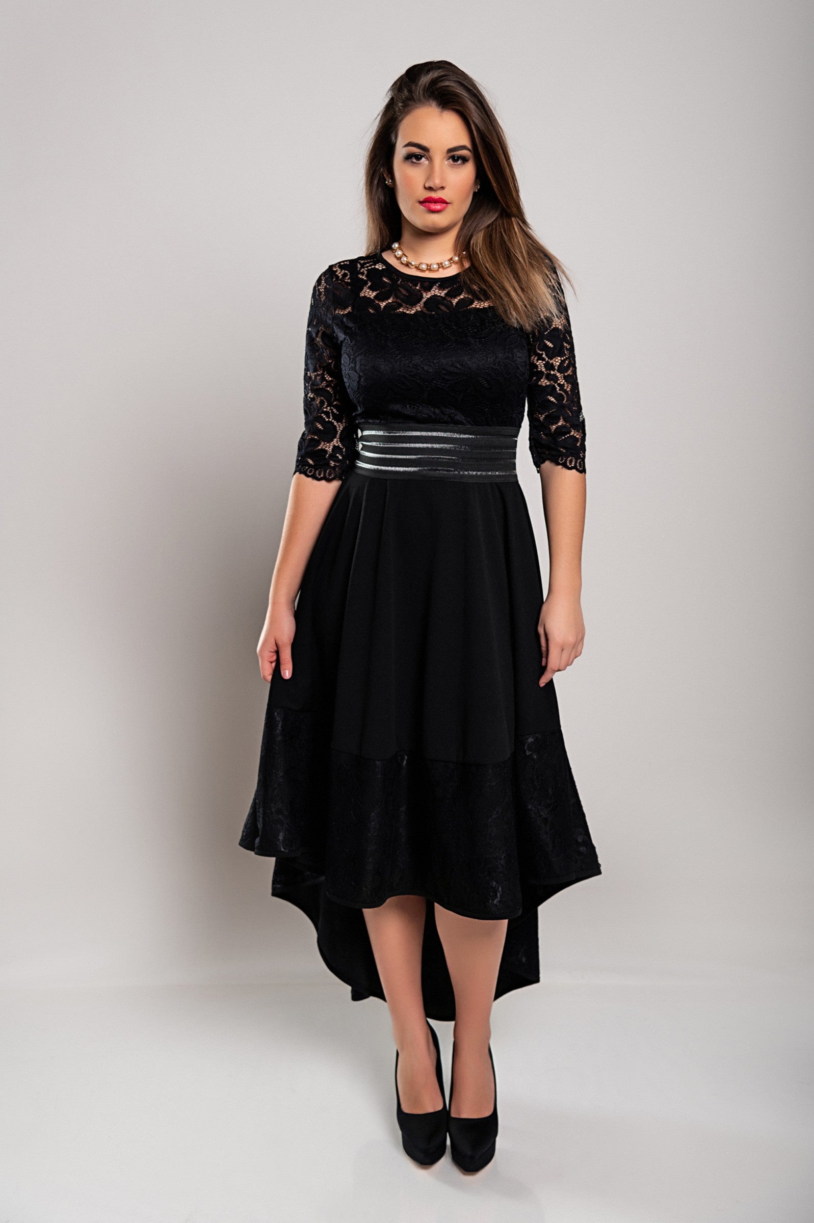 Elegantna črna obleka s čipkastimi detajli in prosojnimi rokavi, asimetrične dolžine.