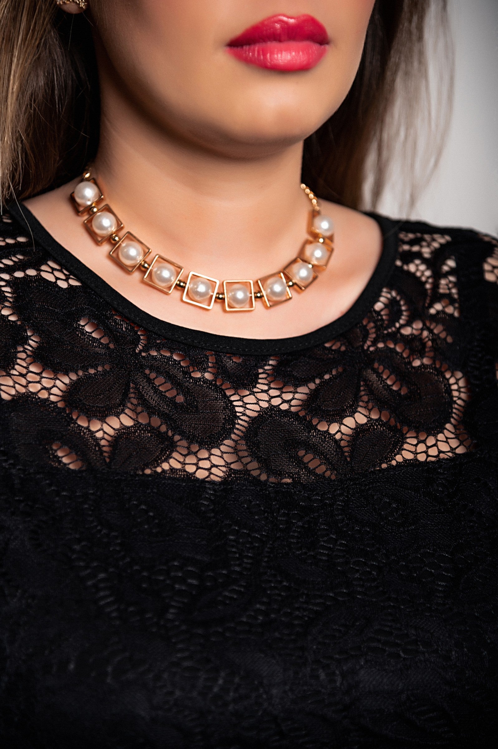 Elegantna črna obleka s čipkastimi detajli in prosojnimi rokavi, asimetrične dolžine.