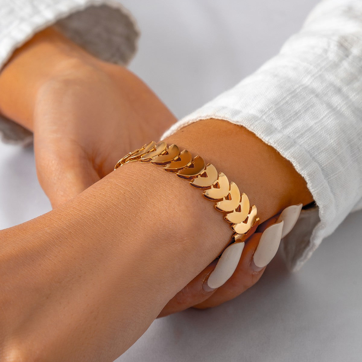 Elegantna zlatna zapestnica iz polkrožnih členov, ki se blešči v svetlobi.