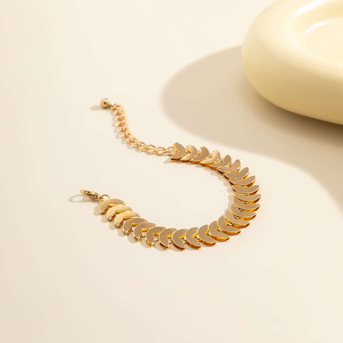 Elegantna zlatna zapestnica iz polkrožnih členov, ki se blešči v svetlobi.