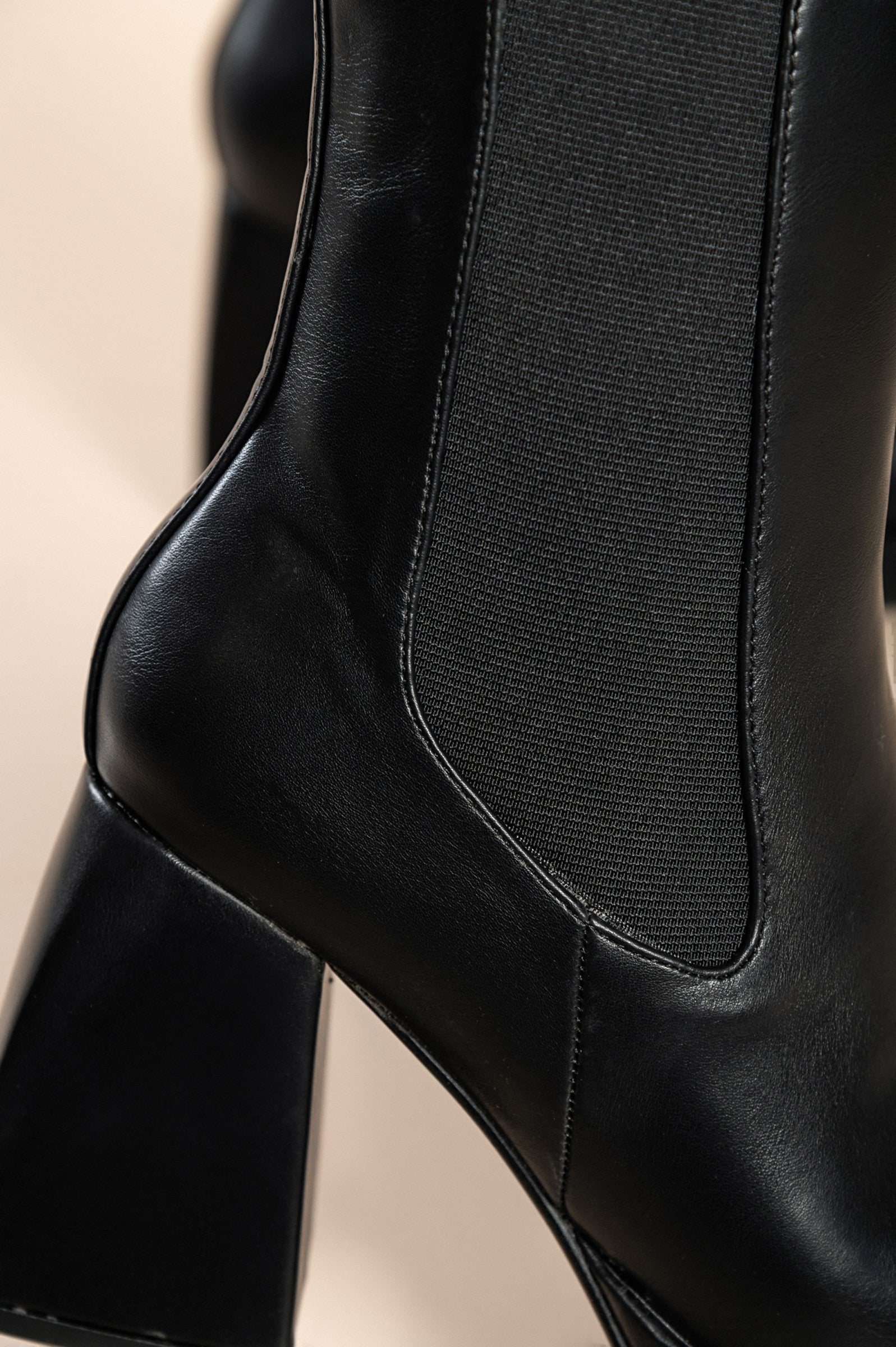 Elegantni črni gležnjarji z visoko peto in zadrgo, kvadratna konica, moderen dizajn.