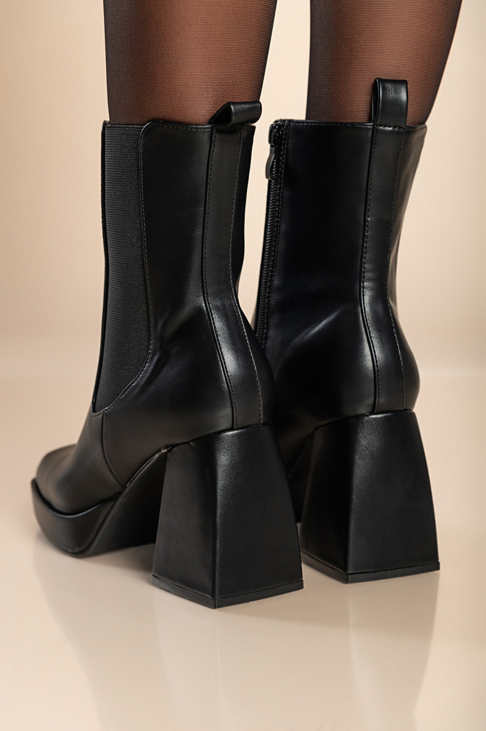 Elegantni črni gležnjarji z visoko peto in zadrgo, kvadratna konica, moderen dizajn.