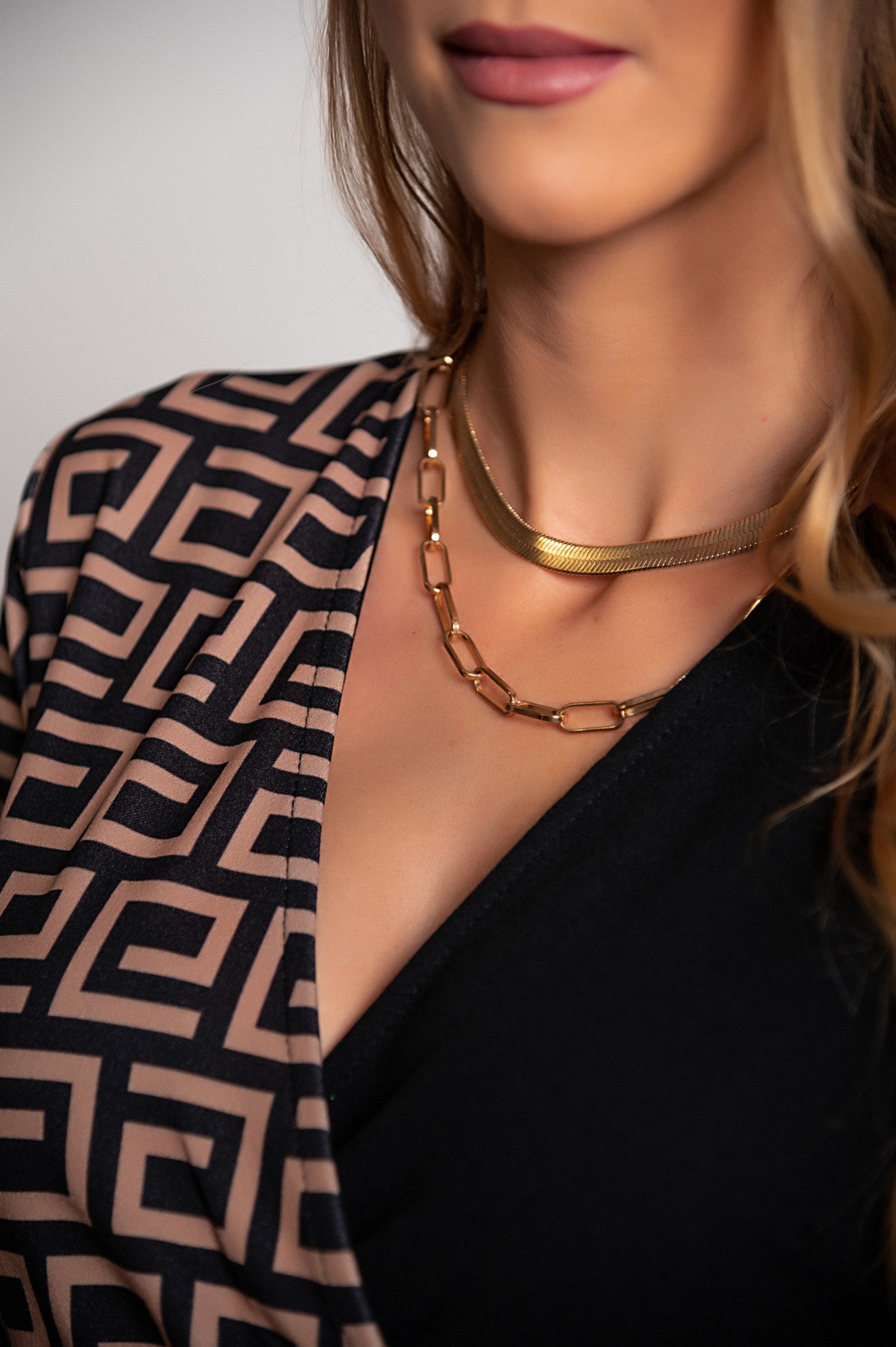 Elegantna črna midi obleka z geometrijskim potiskom, dolgi rokavi in razporkom, izdelana v Italiji.