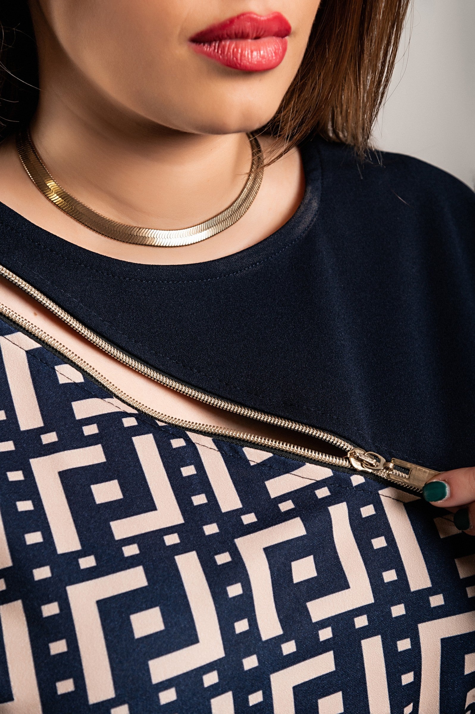 Elegatna modra mini obleka z geometrijskim potiskom, ohlapen zgornji del in oprijeto krilo do sredine stegen.