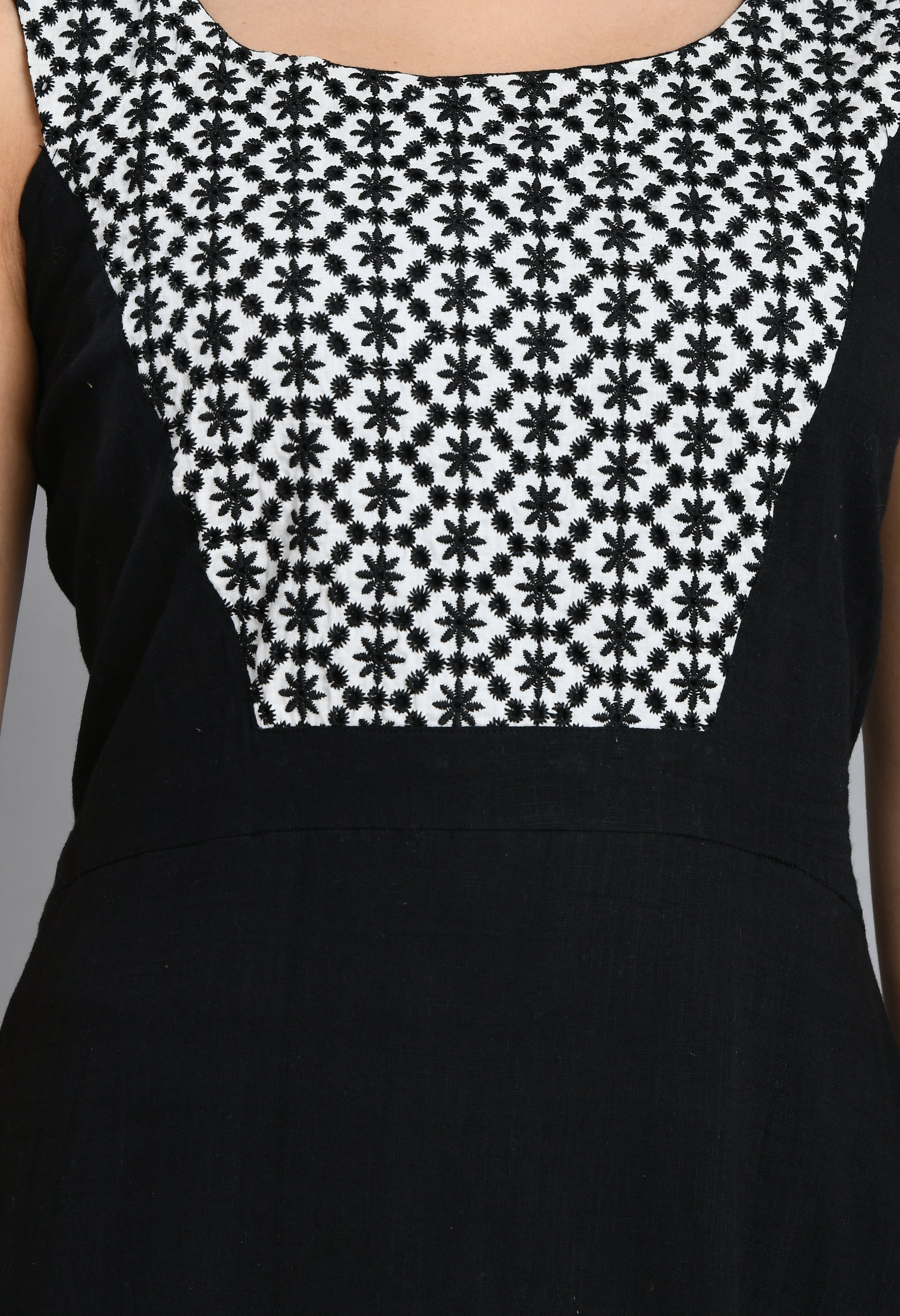 A stylish embroidered black dress featuring a square neck, sleeveless design, and asymmetrical hem, perfect for casual and semi-festive occasions.