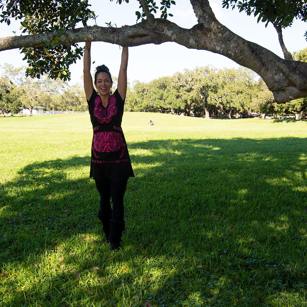 A beautiful embroidered ethnic folk dress featuring vibrant pink floral designs on a black background, showcasing intricate craftsmanship from Puebla, Mexico.