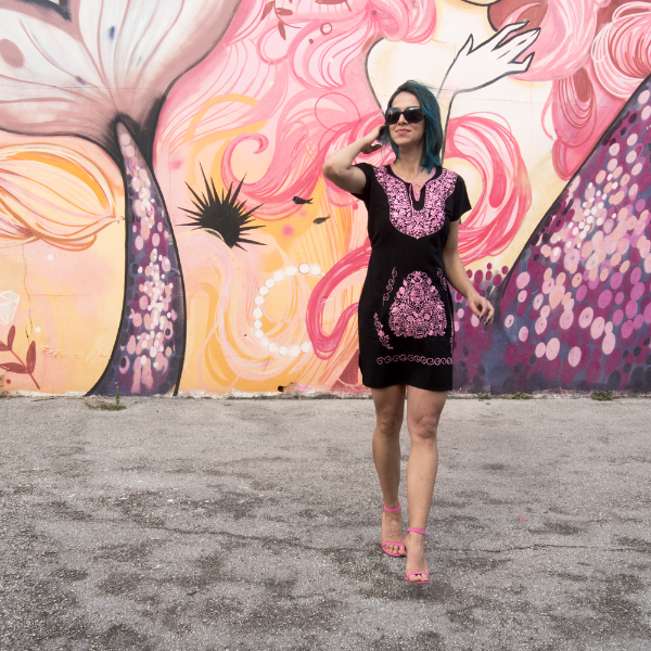 A beautiful embroidered ethnic folk dress featuring vibrant pink floral designs on a black background, showcasing intricate craftsmanship from Puebla, Mexico.