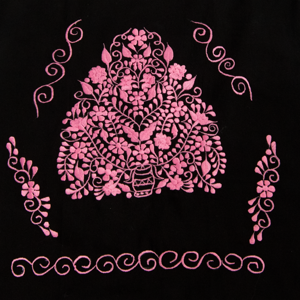 A beautiful embroidered ethnic folk dress featuring vibrant pink floral designs on a black background, showcasing intricate craftsmanship from Puebla, Mexico.