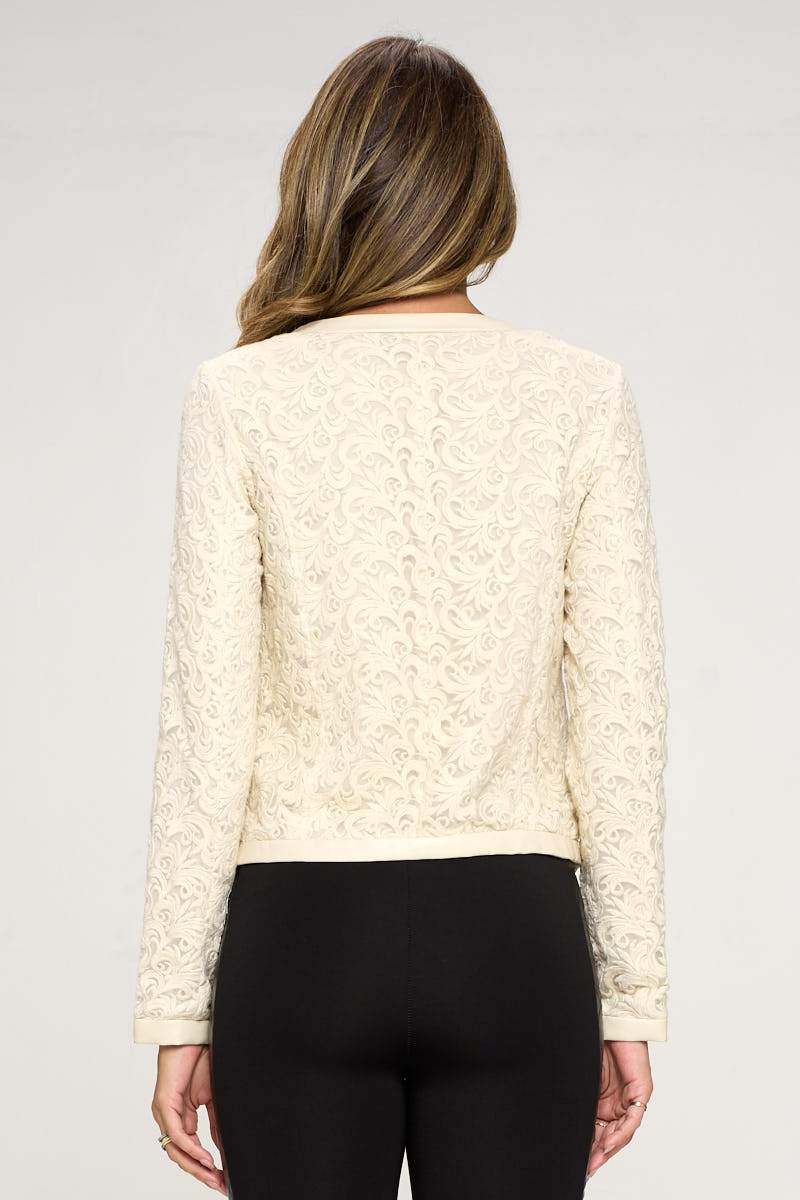 Embroidered zip-up jacket featuring zipper pockets and vegan leather edging, modeled by a woman standing confidently.