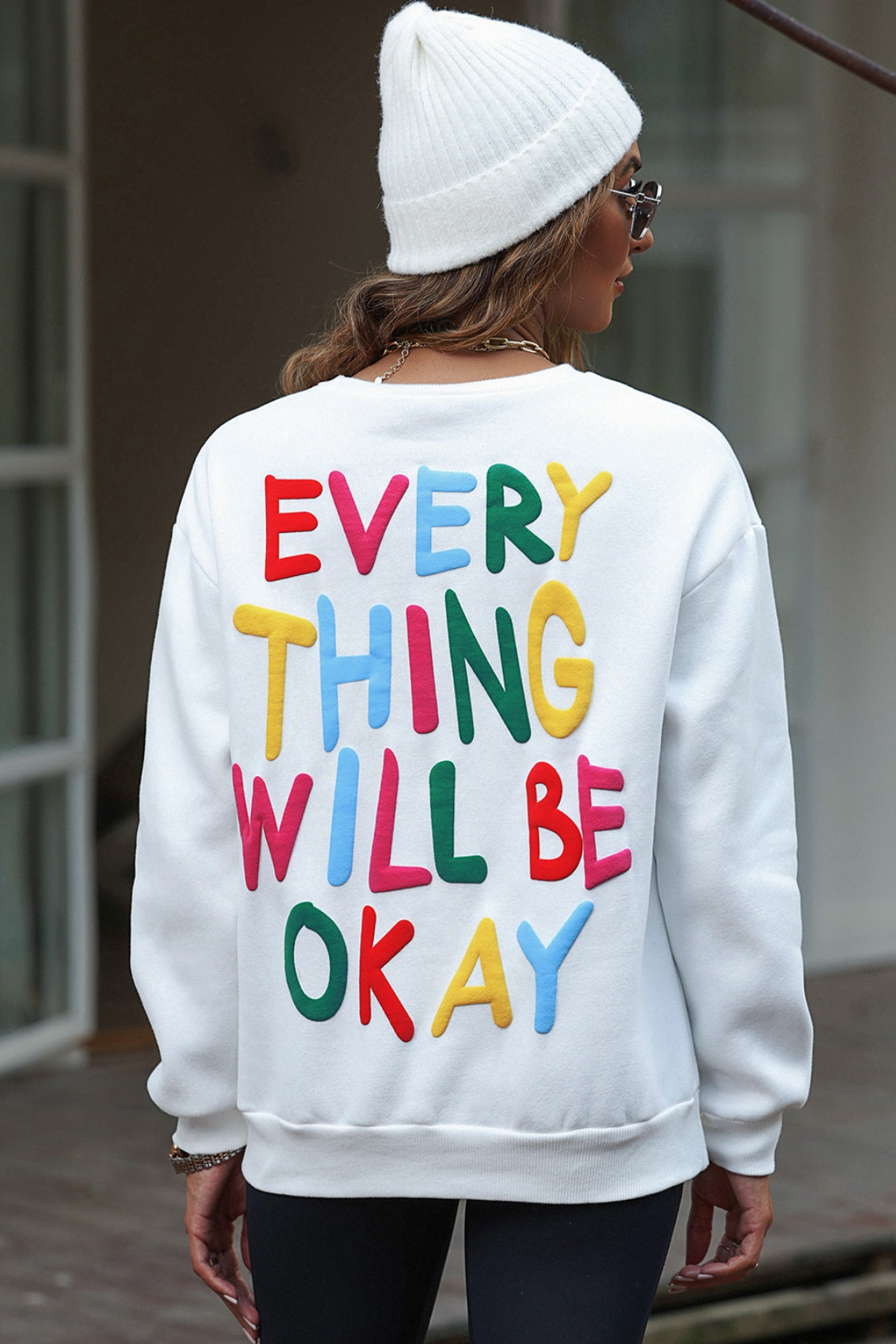 Colorful sweatshirt with 'Everything Will Be Okay' lettering, showcasing a cozy design and vibrant colors.