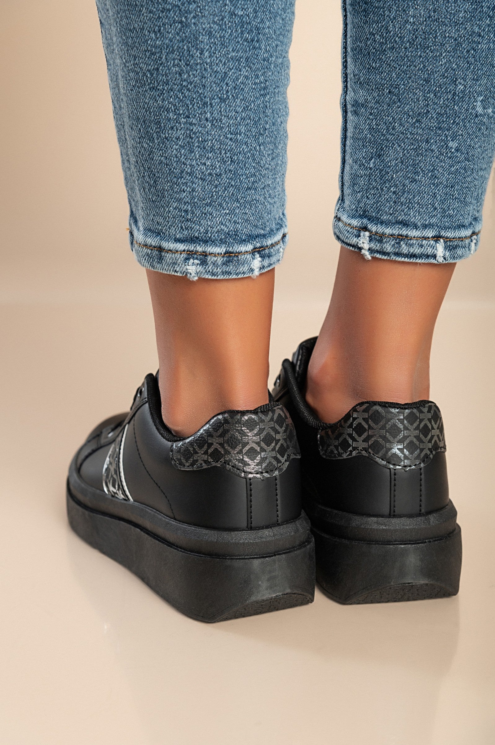Black fashion sneakers with flat sole, lace-up closure, and round toe design, made of high-quality faux leather.