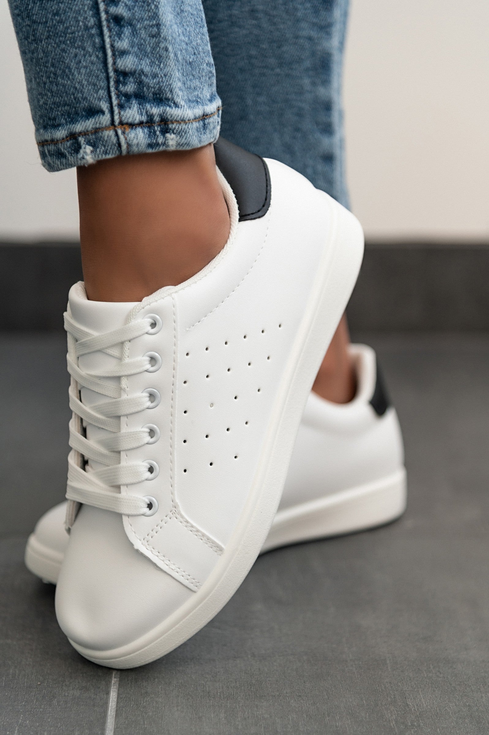 A pair of stylish black fashion sneakers with flat soles, featuring a round toe and bow closure, made from high-quality synthetic leather.