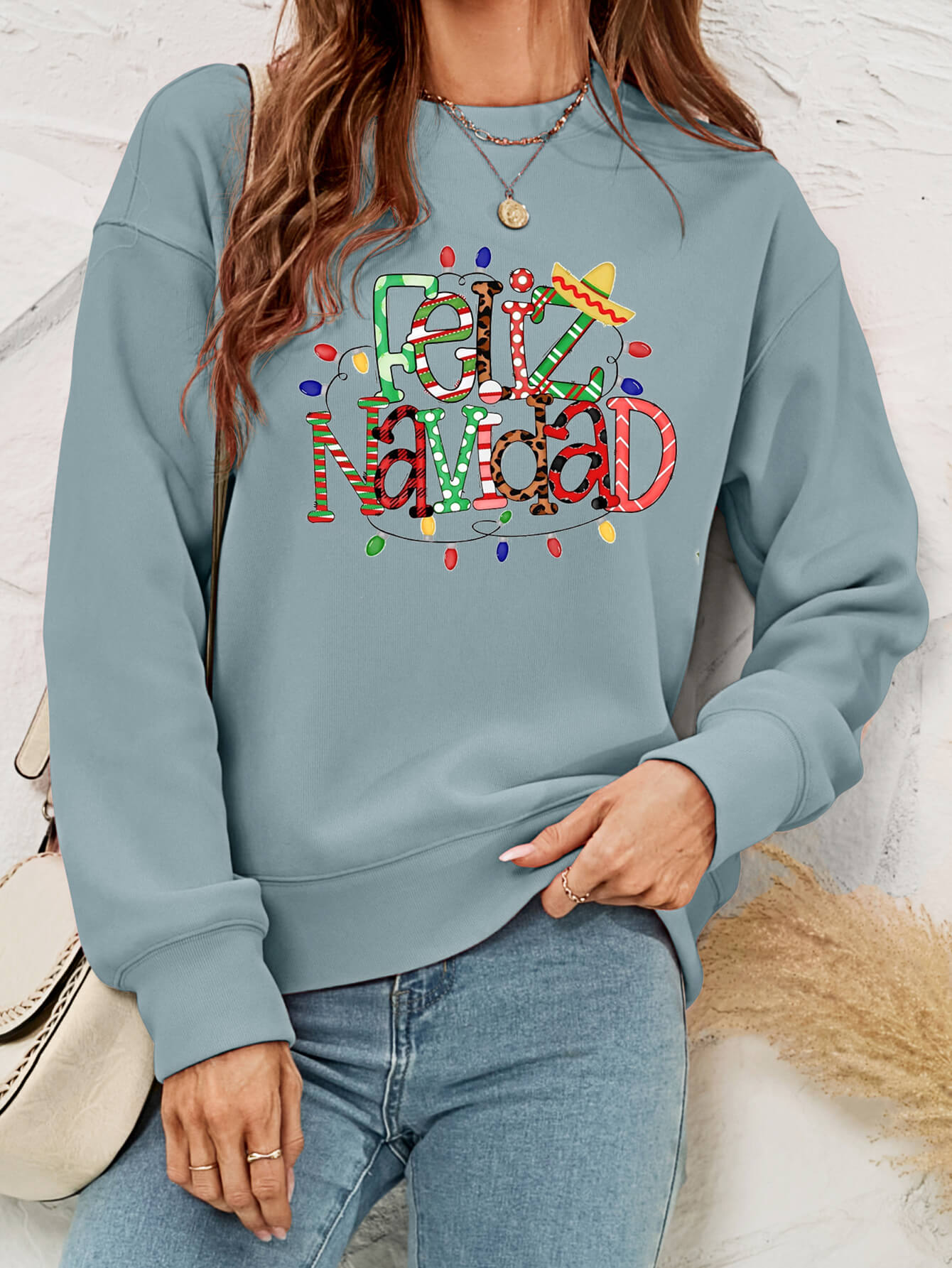 Feliz Navidad Graphic Crewneck Sweatshirt in a studio setting, featuring a festive design and casual style.