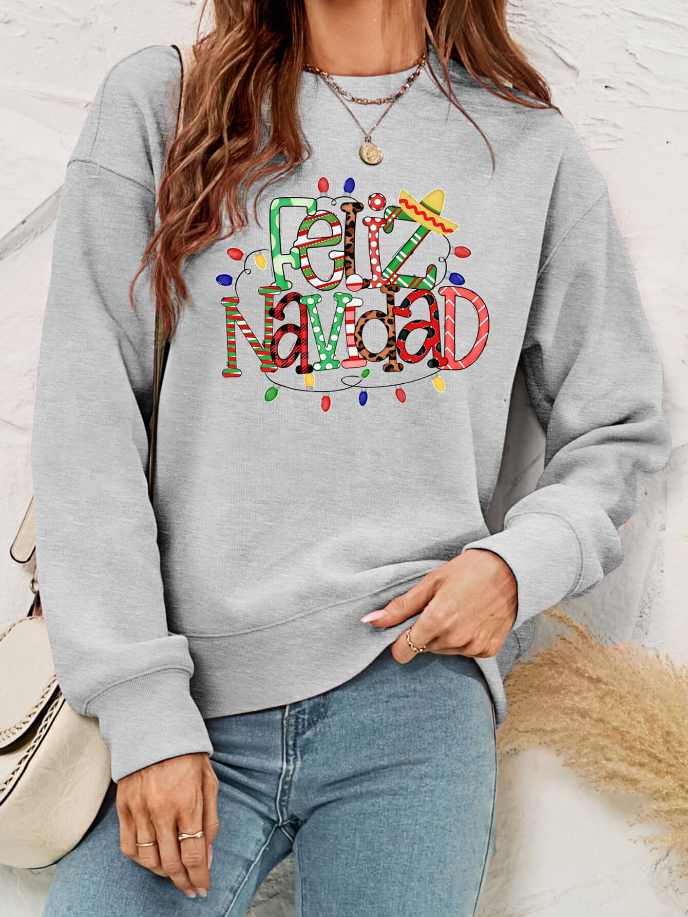 Feliz Navidad Graphic Crewneck Sweatshirt in a studio setting, featuring a festive design and casual style.
