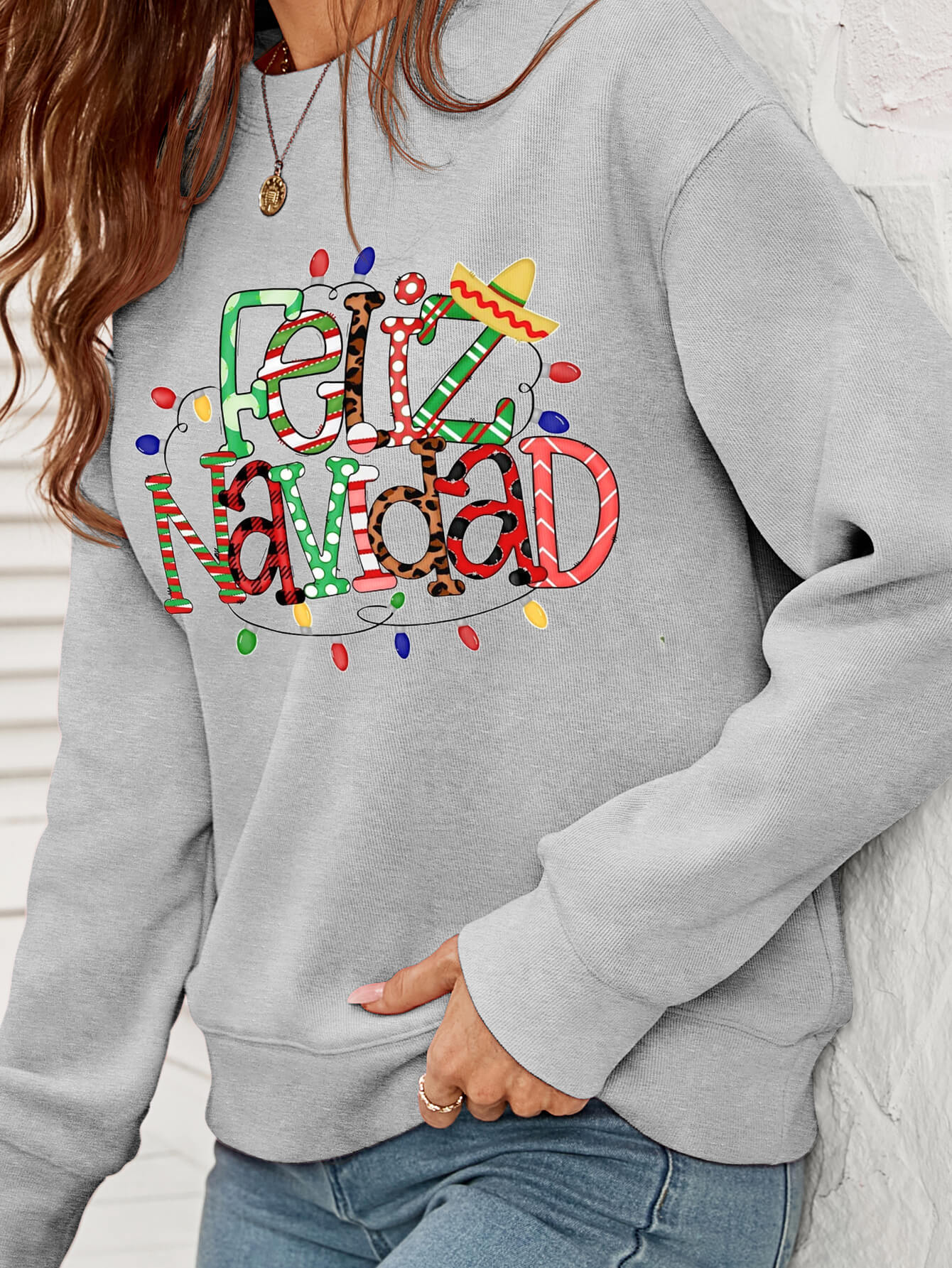 Feliz Navidad Graphic Crewneck Sweatshirt in a studio setting, featuring a festive design and casual style.