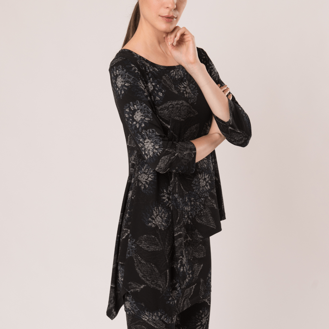 Florence side flow Top featuring a round neckline, three-quarter sleeves, and a softly draped side flowing hemline with a floral print in neutral shades.