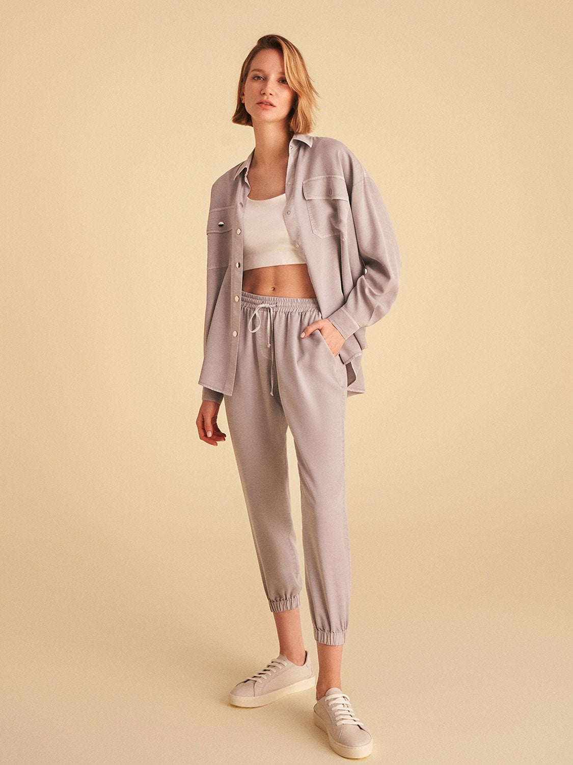 Flowy shirt with pockets, featuring long sleeves, snap buttons, and vibrant digital collage patterns in soft shades.