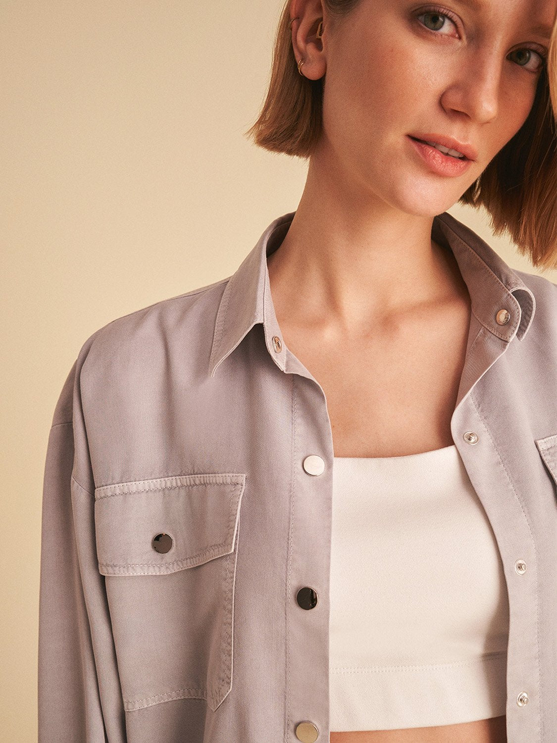 Flowy shirt with pockets, featuring long sleeves, snap buttons, and vibrant digital collage patterns in soft shades.