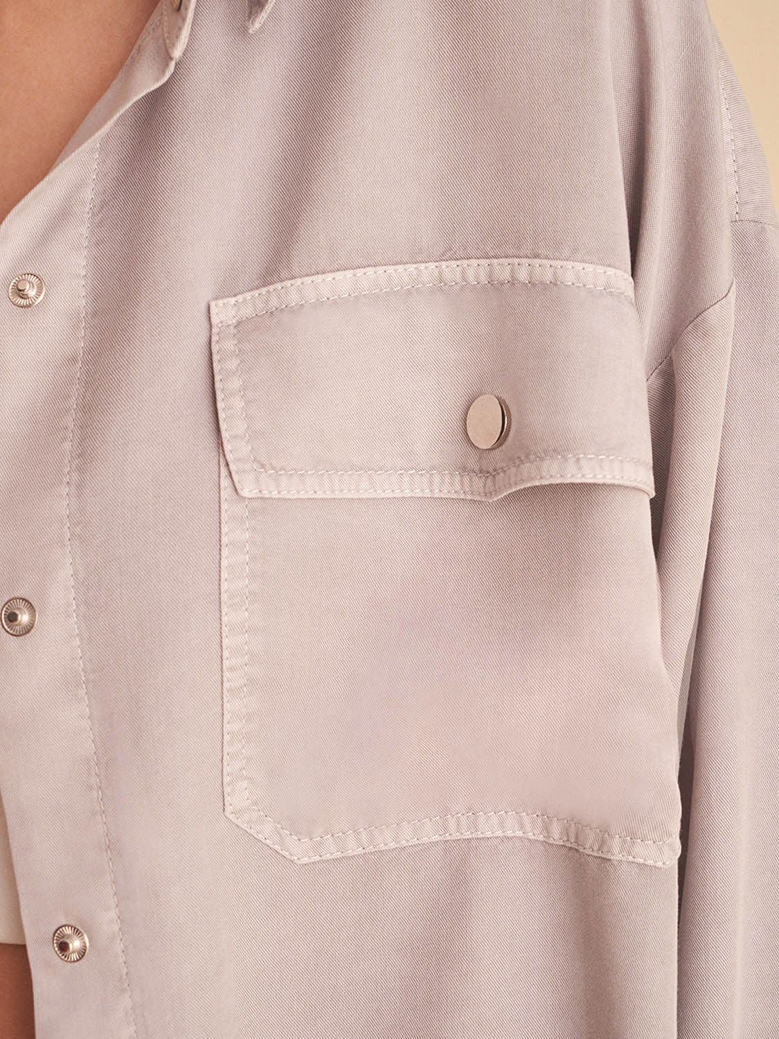 Flowy shirt with pockets, featuring long sleeves, snap buttons, and vibrant digital collage patterns in soft shades.