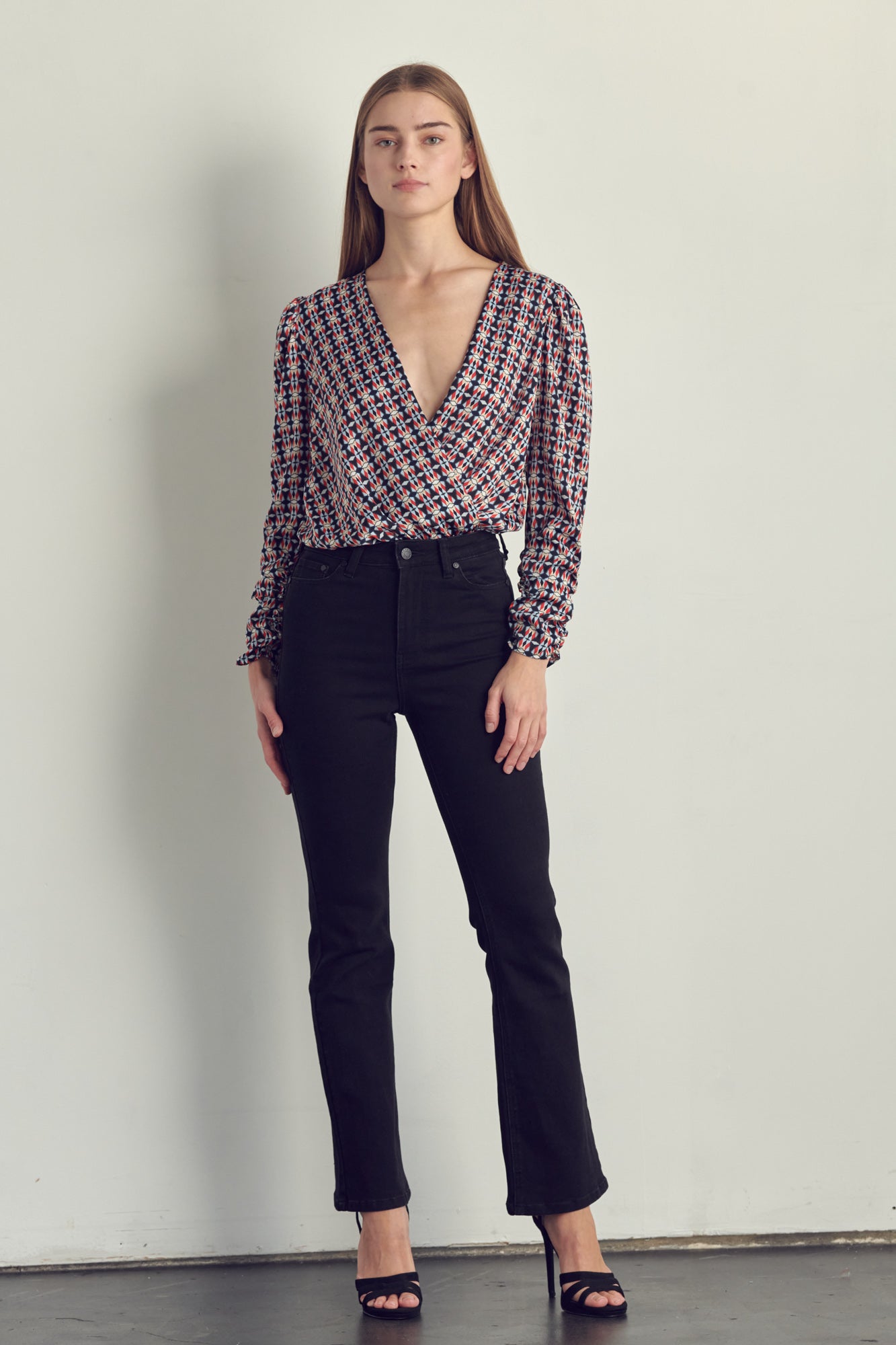 Ruched long sleeve surplice bodysuit in satin abstract print, featuring a stylish neckline and ruched cuffs.