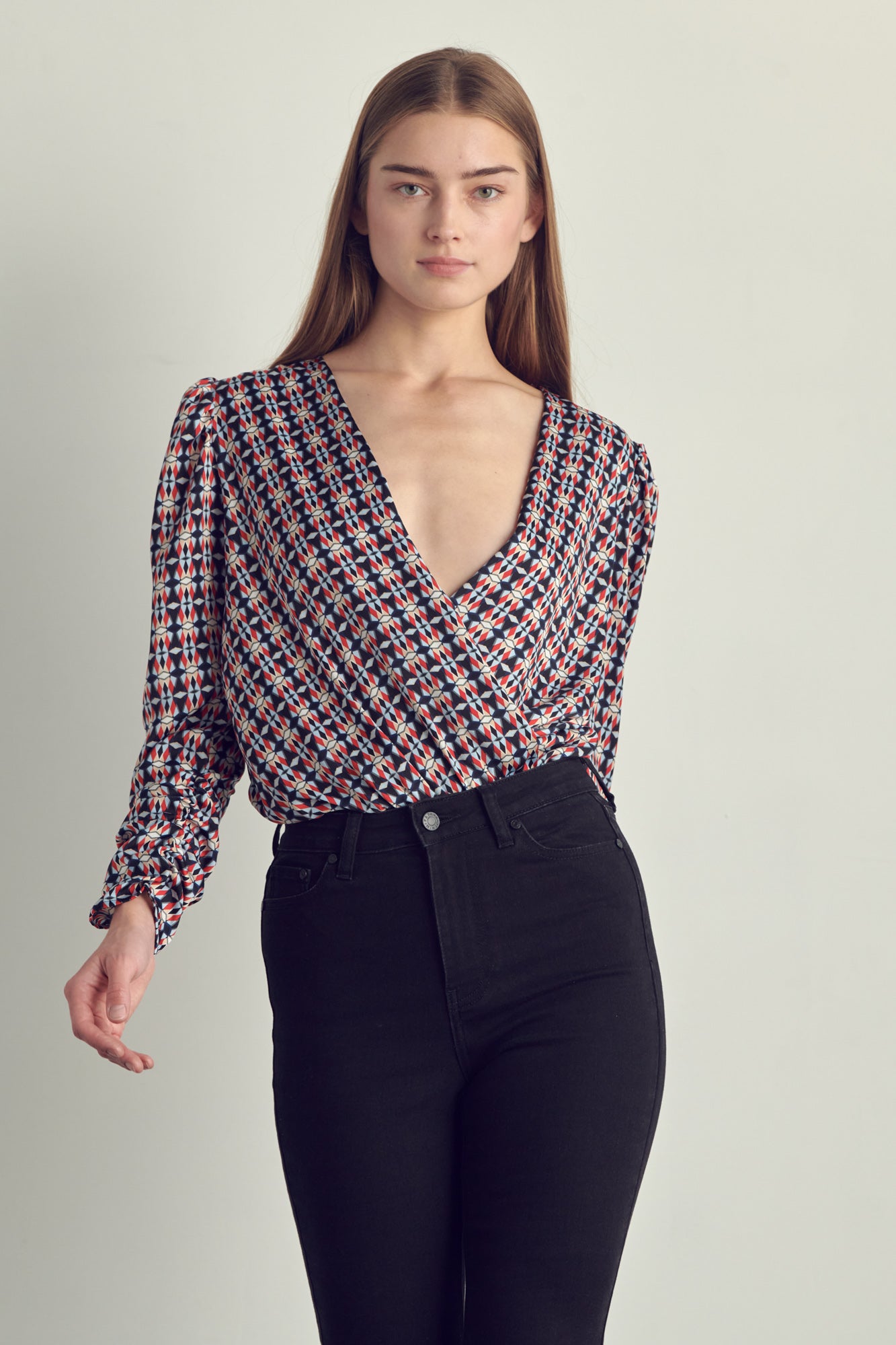 Ruched long sleeve surplice bodysuit in satin abstract print, featuring a stylish neckline and ruched cuffs.