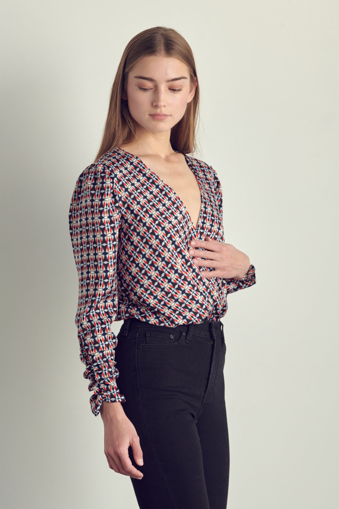 Ruched long sleeve surplice bodysuit in satin abstract print, featuring a stylish neckline and ruched cuffs.