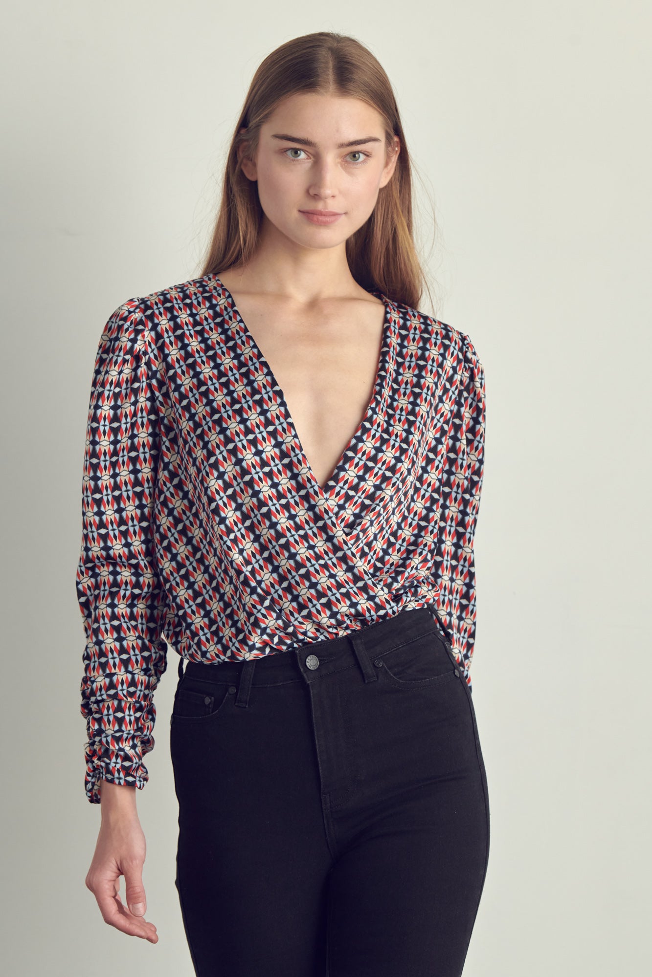 Ruched long sleeve surplice bodysuit in satin abstract print, featuring a stylish neckline and ruched cuffs.