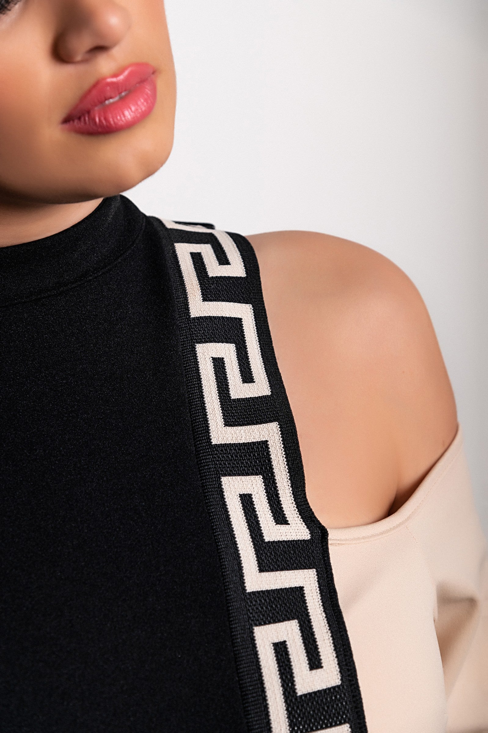 Geometric print top Nelyna in black and beige with high neck and cold shoulder design, showcasing long sleeves and stylish pattern.