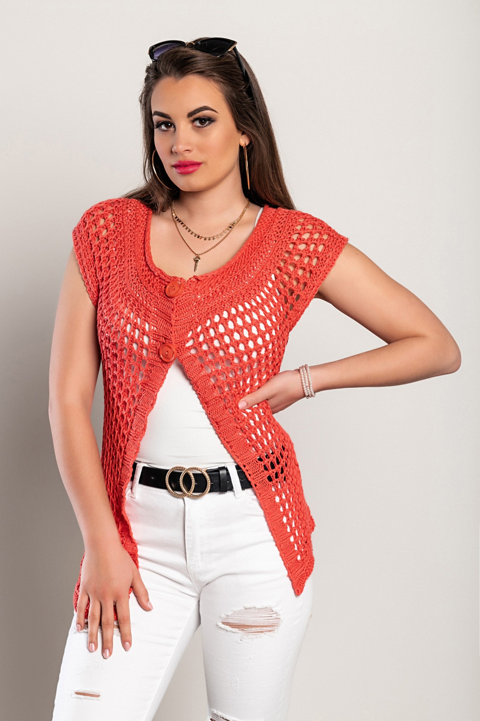 Rdeča grobo pletena jopica s kratkimi rokavi, asimetrične dolžine, z gumbi na sprednji strani in okroglim izrezom.