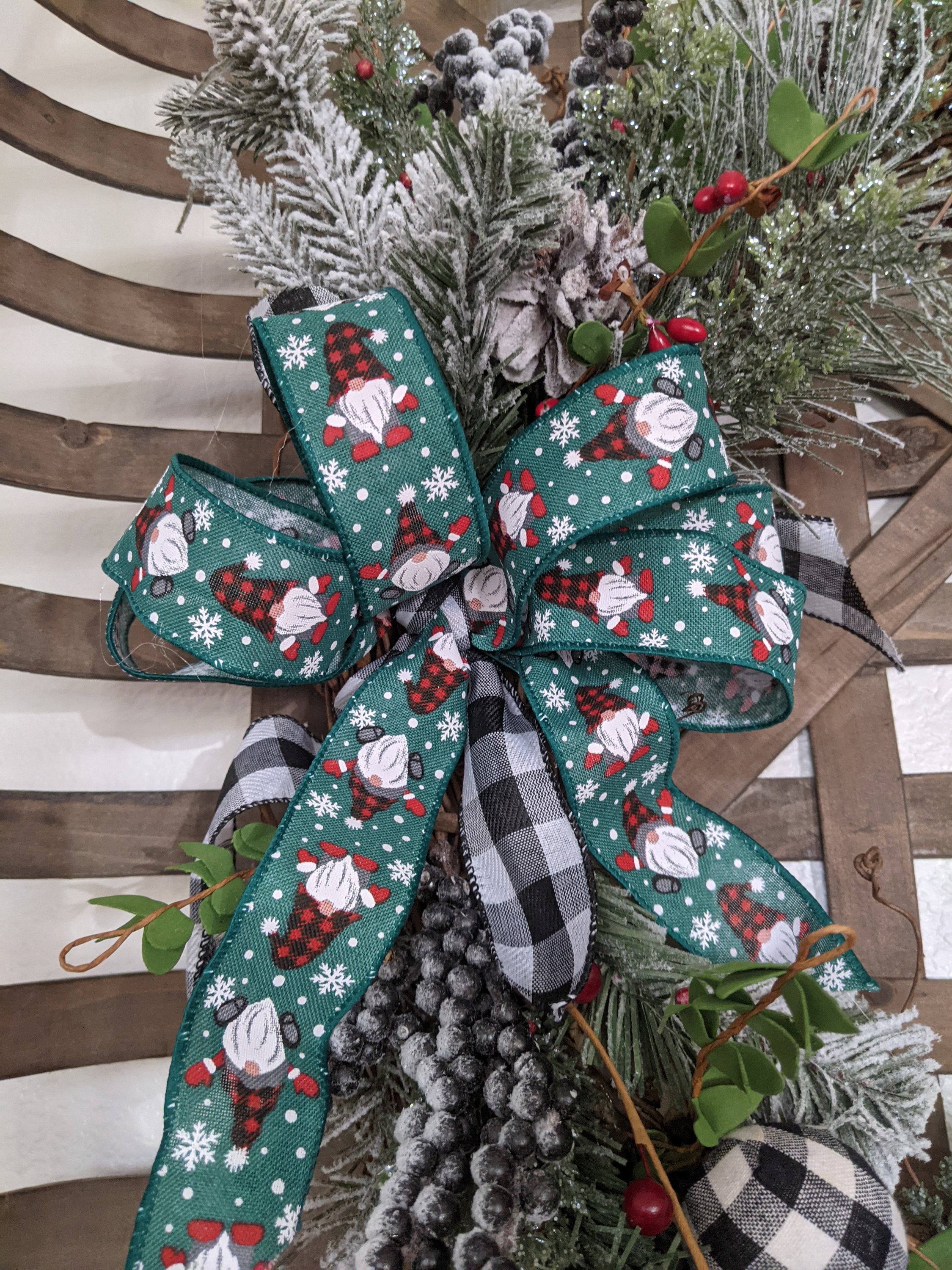 A handmade 18-inch grapevine wreath featuring gnome accents, buffalo plaid, and greenery, perfect for winter and Christmas decor.