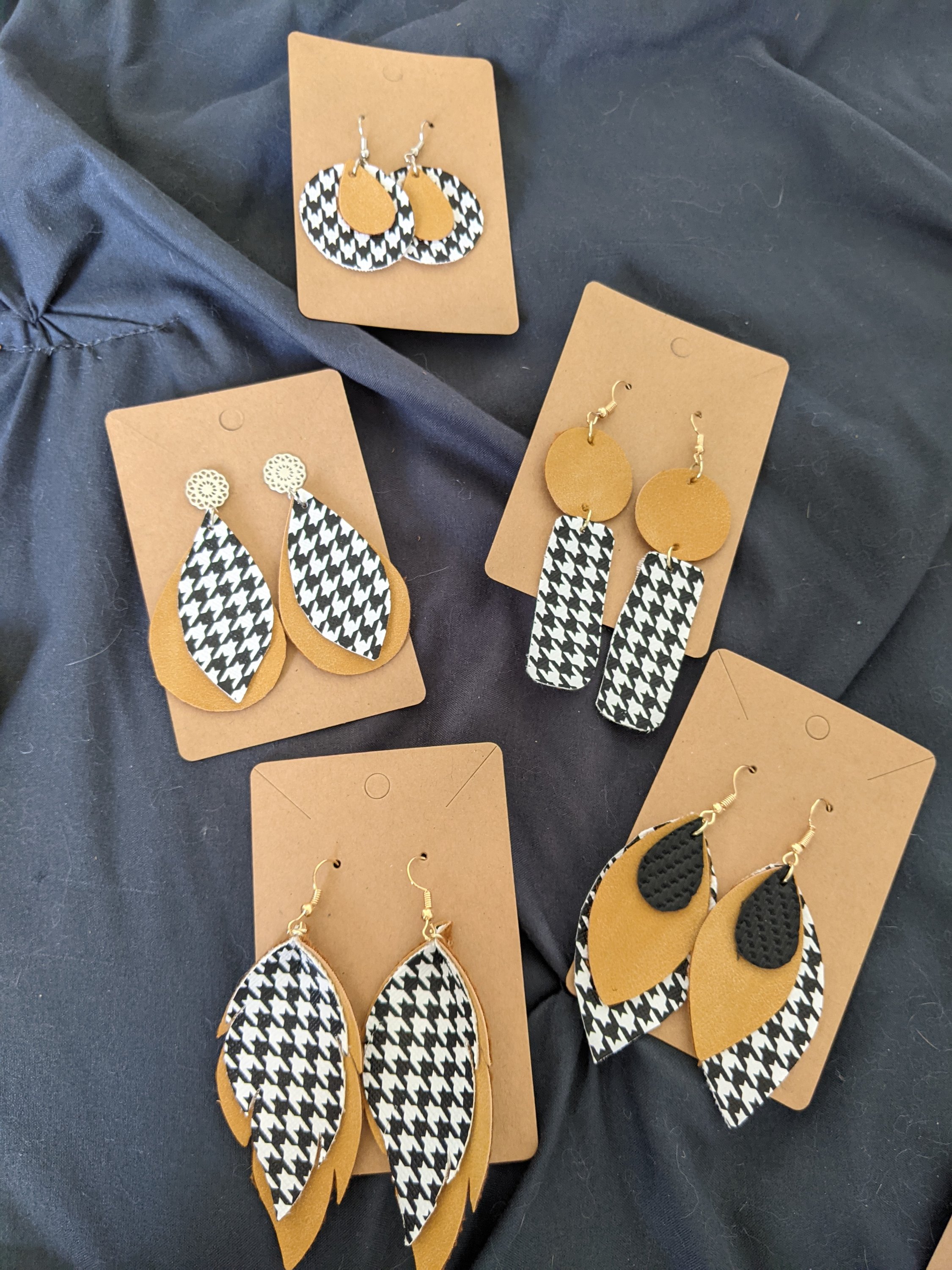 A pair of handmade earrings featuring a trendy houndstooth pattern with camel faux leather accents, measuring about an inch and a half.