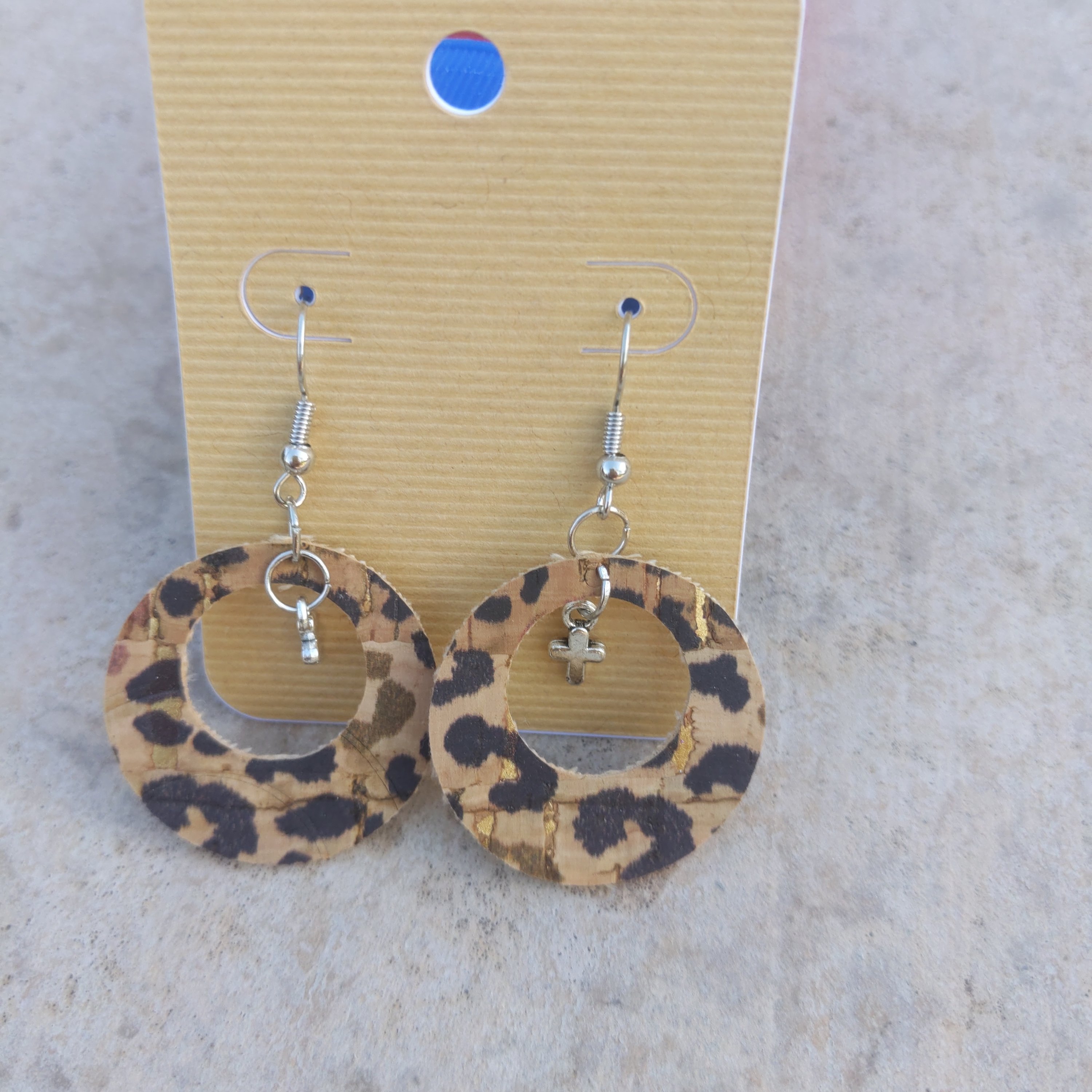 Handmade leopard cork earrings featuring elegant silver cross charms, showcasing a unique and stylish design.