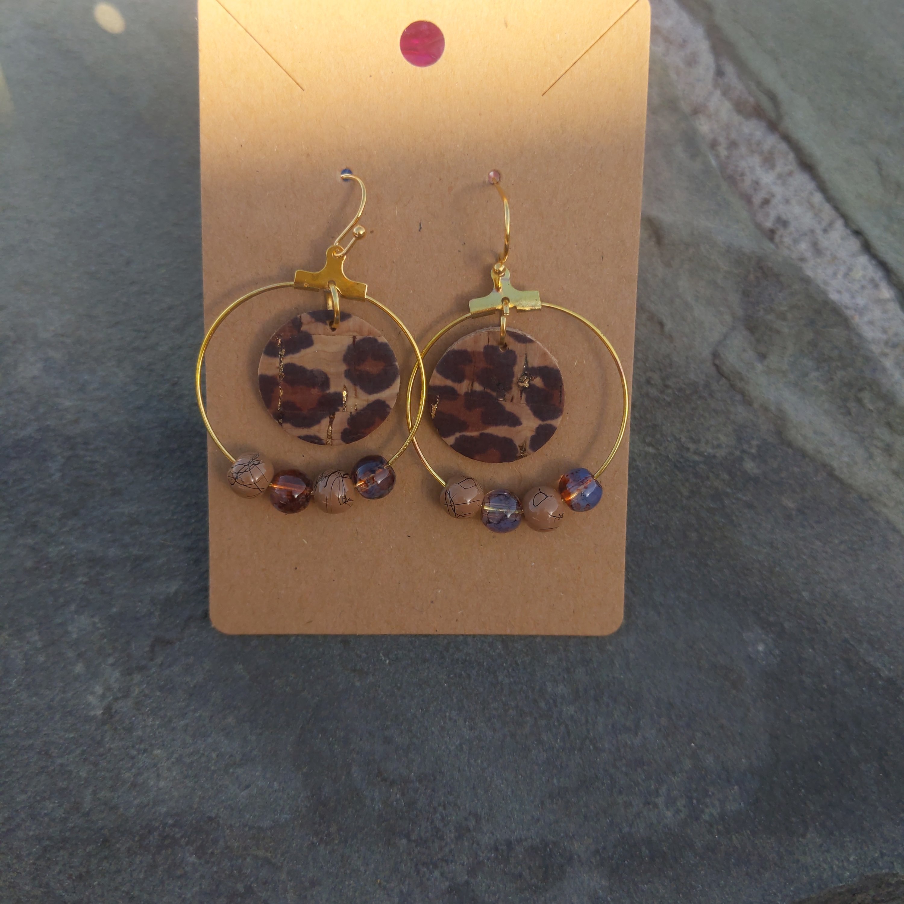 Handmade leopard cork hoop earrings adorned with marbled beads in shades of brown, showcasing a unique and stylish design.
