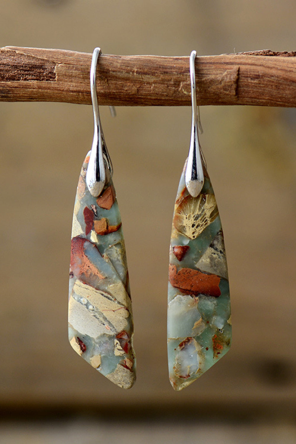 A pair of handmade dangle earrings featuring natural stones, copper, and gold plating, showcasing unique patterns and modern design.