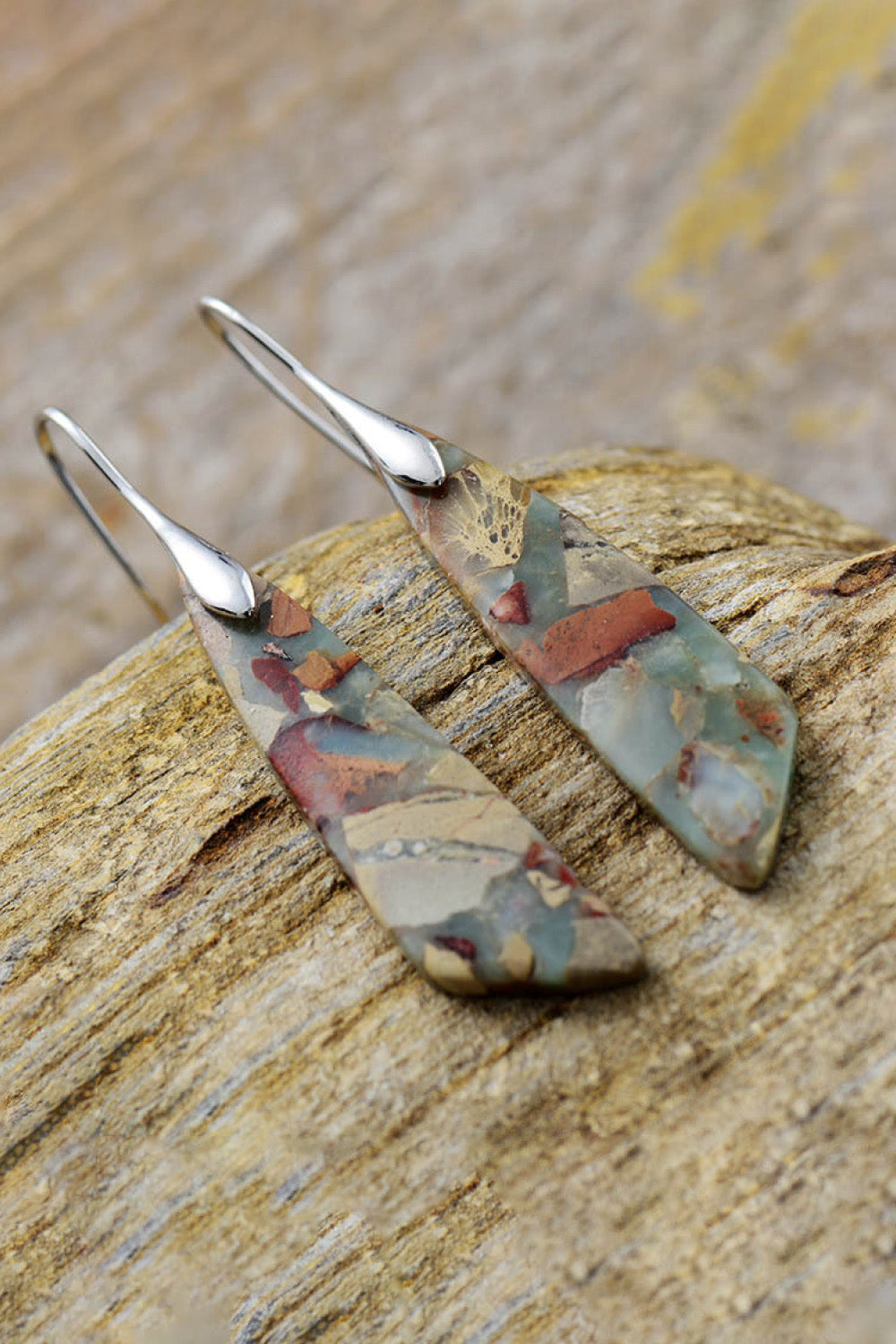 A pair of handmade dangle earrings featuring natural stones, copper, and gold plating, showcasing unique patterns and modern design.