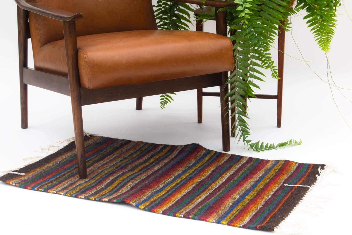 Handmade wool rug featuring colorful stripes and geometric patterns, crafted by artisans in Oaxaca, Mexico.
