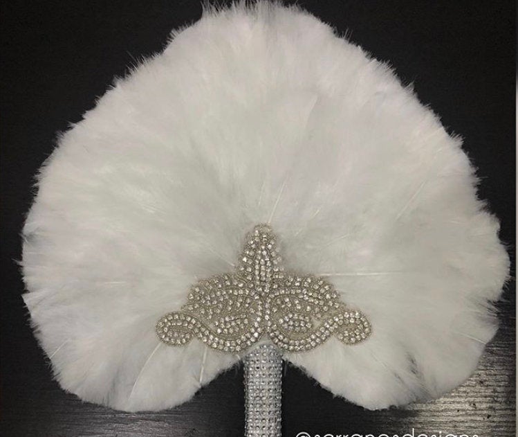 A beautiful heart-shaped fur feather hand fan, featuring fluffy feathers and a wooden handle, perfect for bridal occasions.