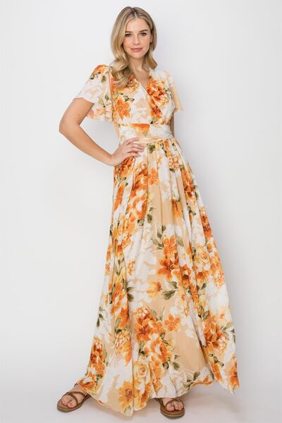 A beautiful floral tie back short sleeve slit maxi dress featuring a vibrant floral print, short sleeves, and a stylish slit for added allure.
