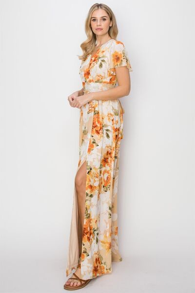 A beautiful floral tie back short sleeve slit maxi dress featuring a vibrant floral print, short sleeves, and a stylish slit for added allure.