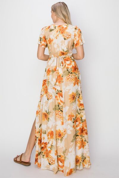 A beautiful floral tie back short sleeve slit maxi dress featuring a vibrant floral print, short sleeves, and a stylish slit for added allure.
