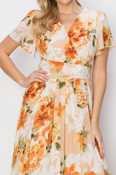 A beautiful floral tie back short sleeve slit maxi dress featuring a vibrant floral print, short sleeves, and a stylish slit for added allure.