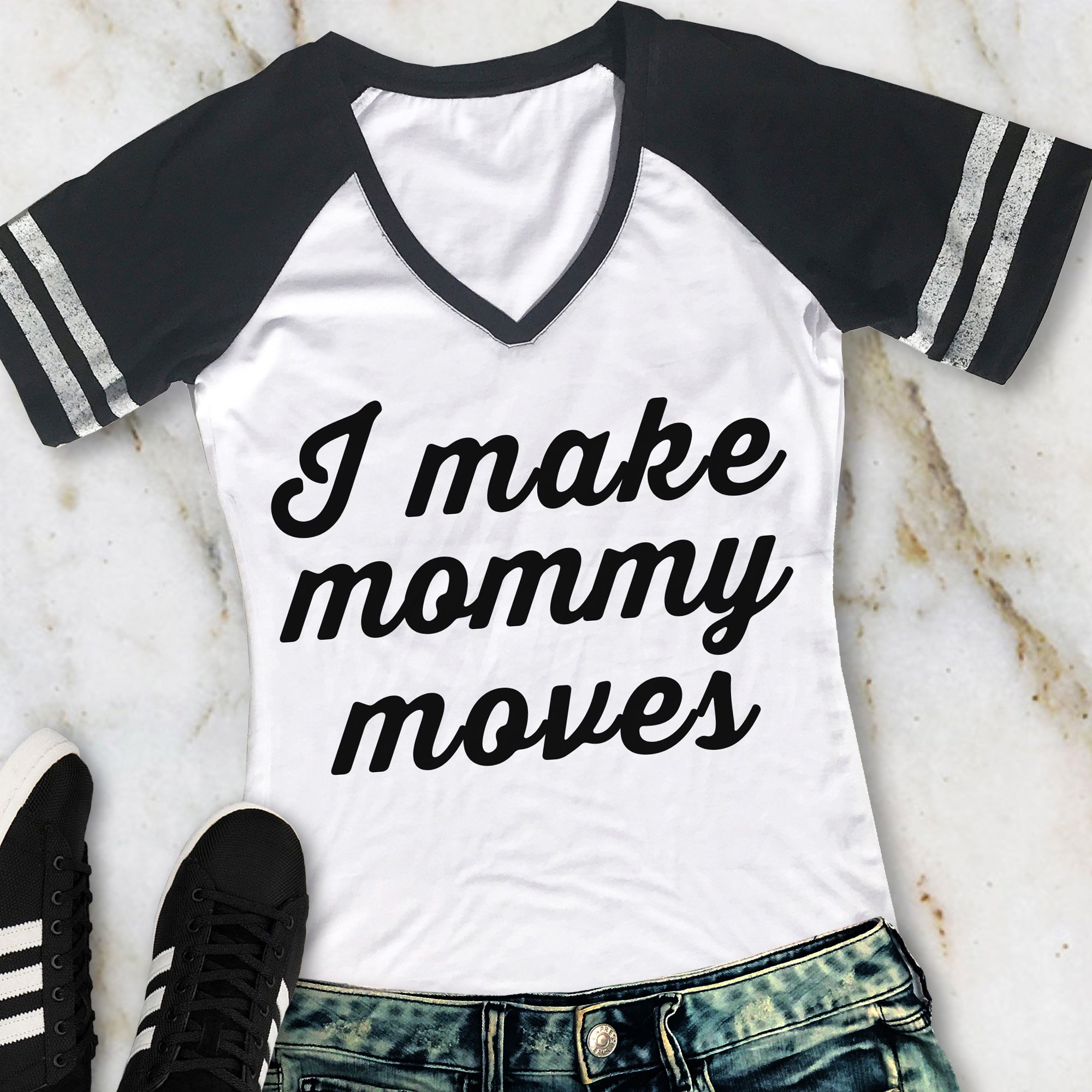 A stylish 'I MAKE MOMMY MOVES' V-neck shirt in black with gray sleeves, showcasing its comfortable fit and trendy design.