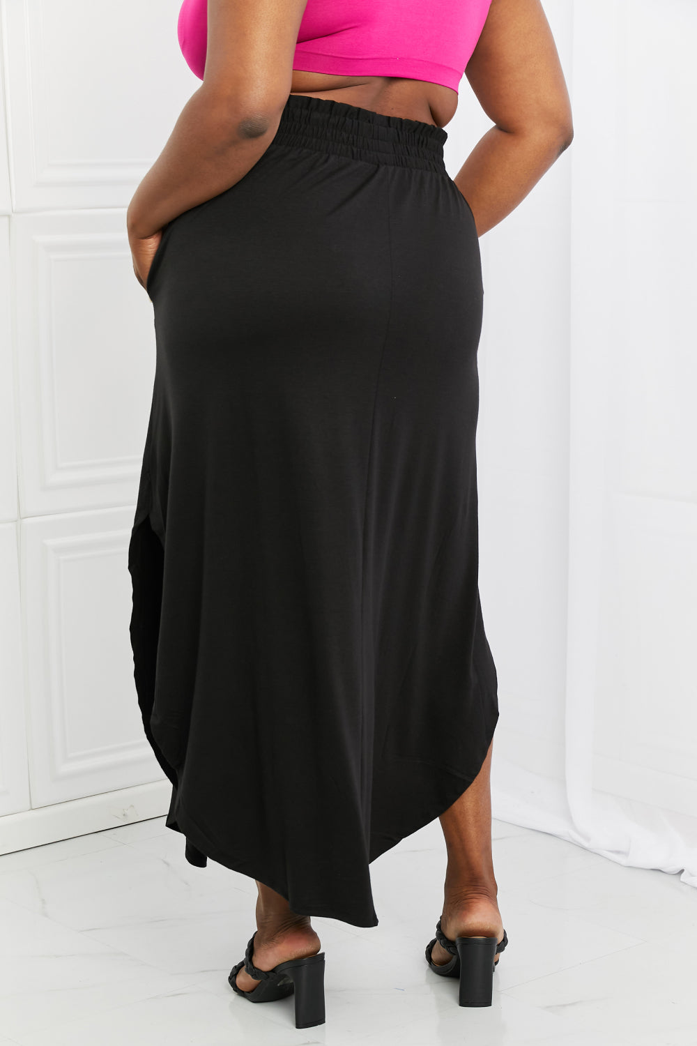 Elegant black maxi skirt with smocked waist and side slit, featuring pockets for convenience.