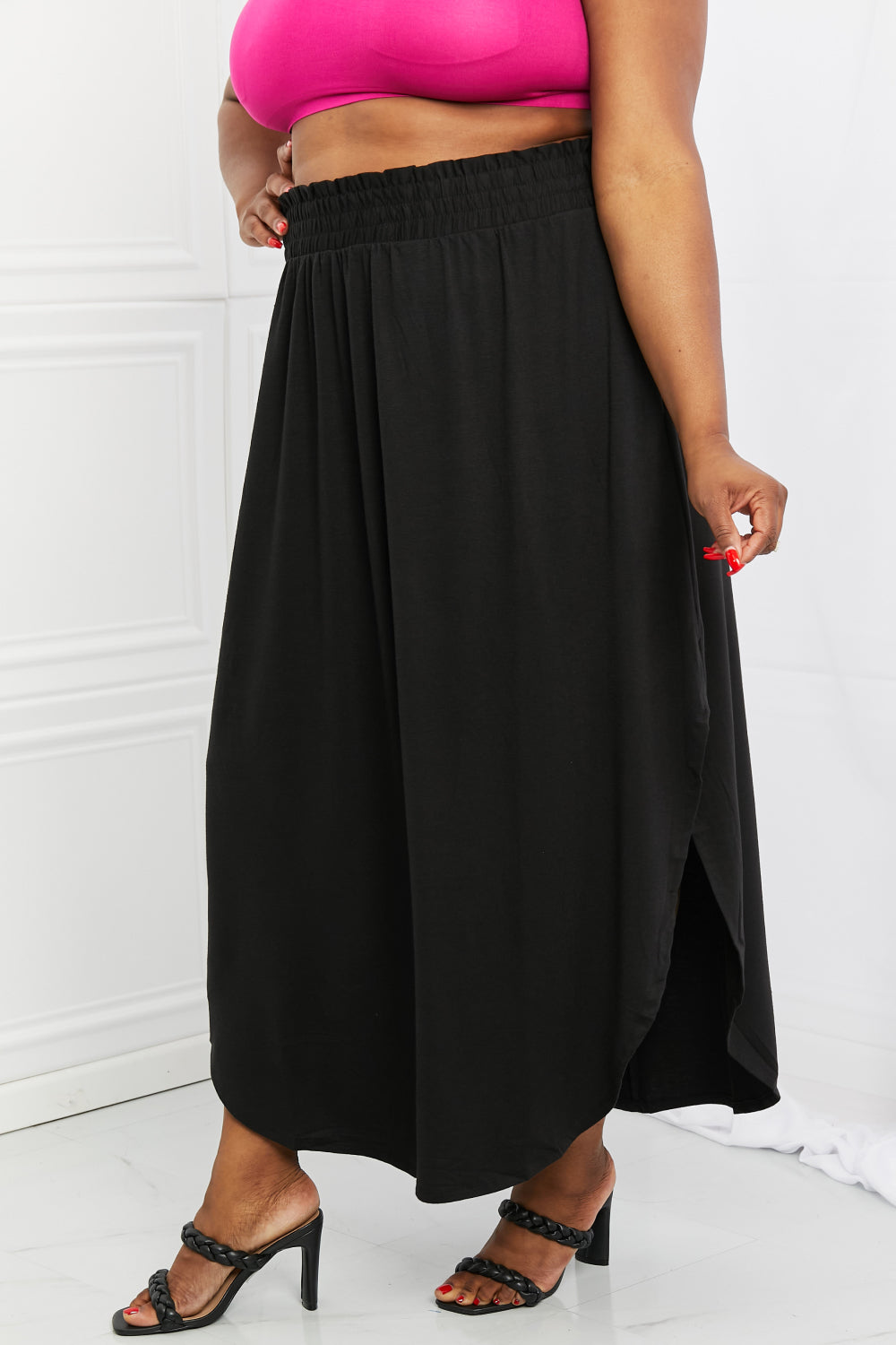 Elegant black maxi skirt with smocked waist and side slit, featuring pockets for convenience.