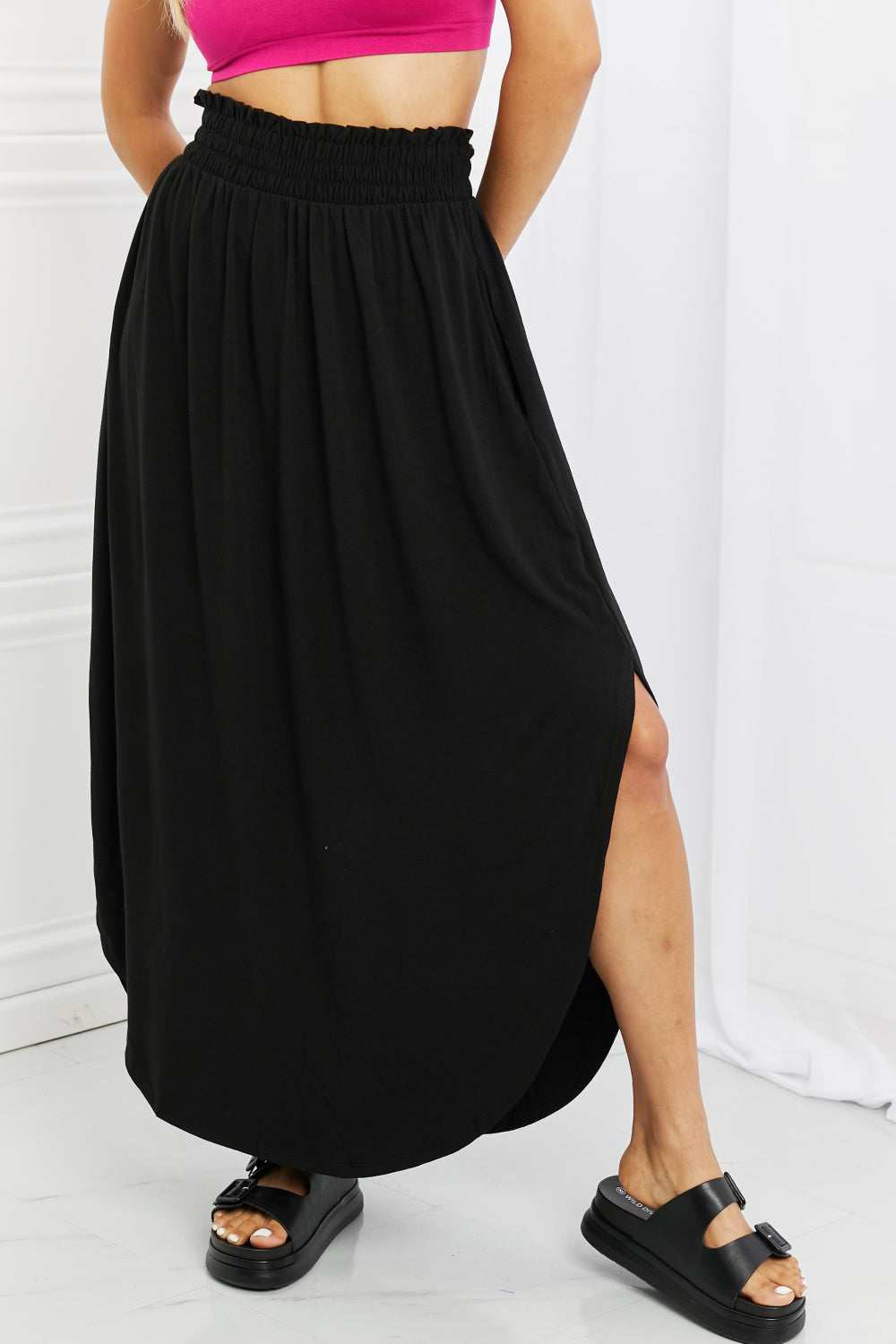Elegant black maxi skirt with smocked waist and side slit, featuring pockets for convenience.