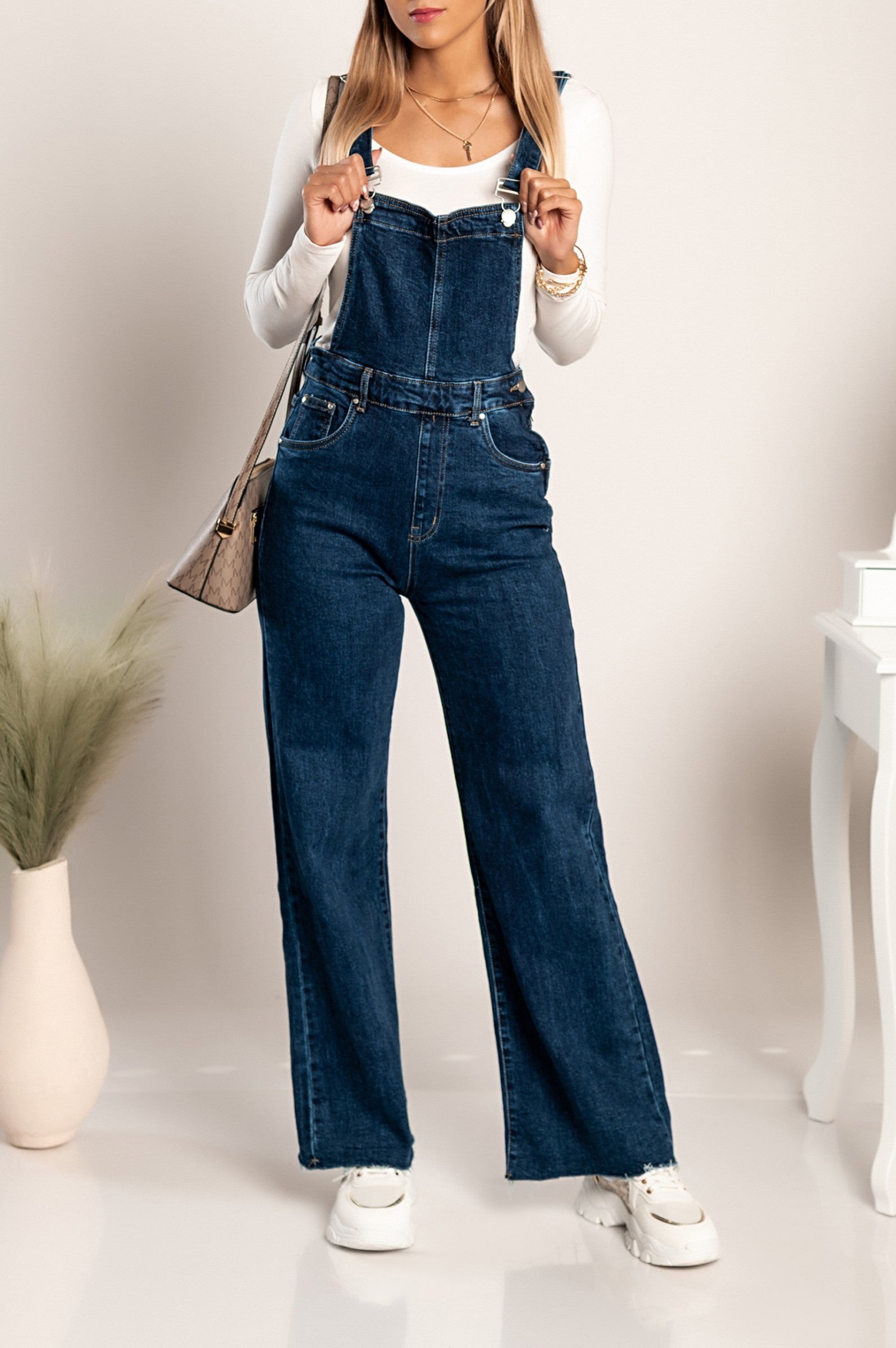 Dark denim jumpsuit Chiessa with adjustable straps and frayed hem, featuring side and back pockets.