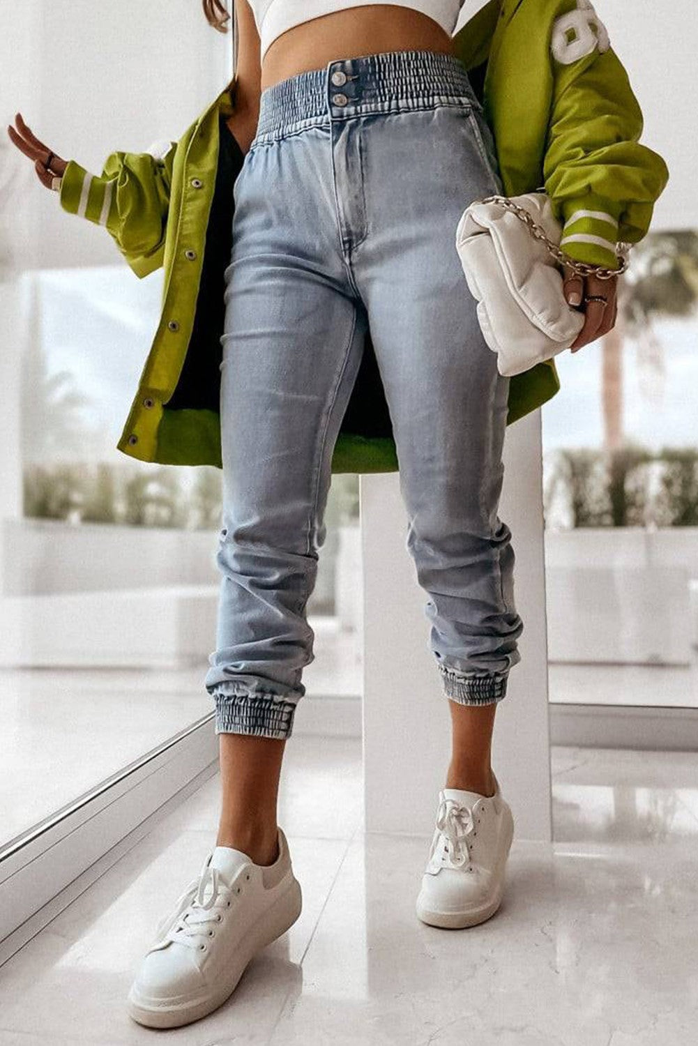 Light blue jeans with elastic waist, featuring button closure and side pockets, designed for comfort and style.