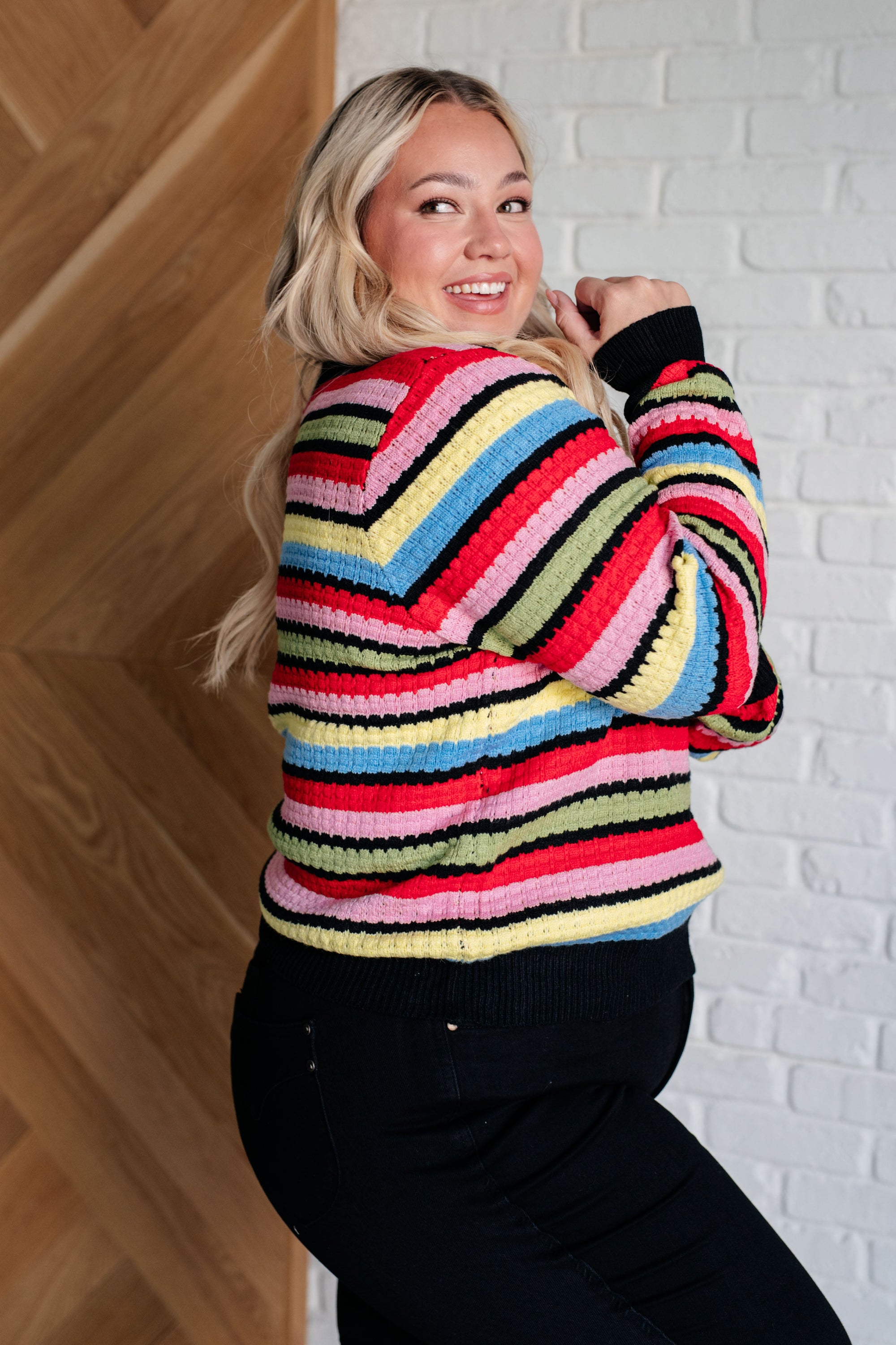 A cozy Keep Dreaming Striped Sweater featuring a scalloped crew neckline and vibrant multi-colored stripes, perfect for stylish comfort.