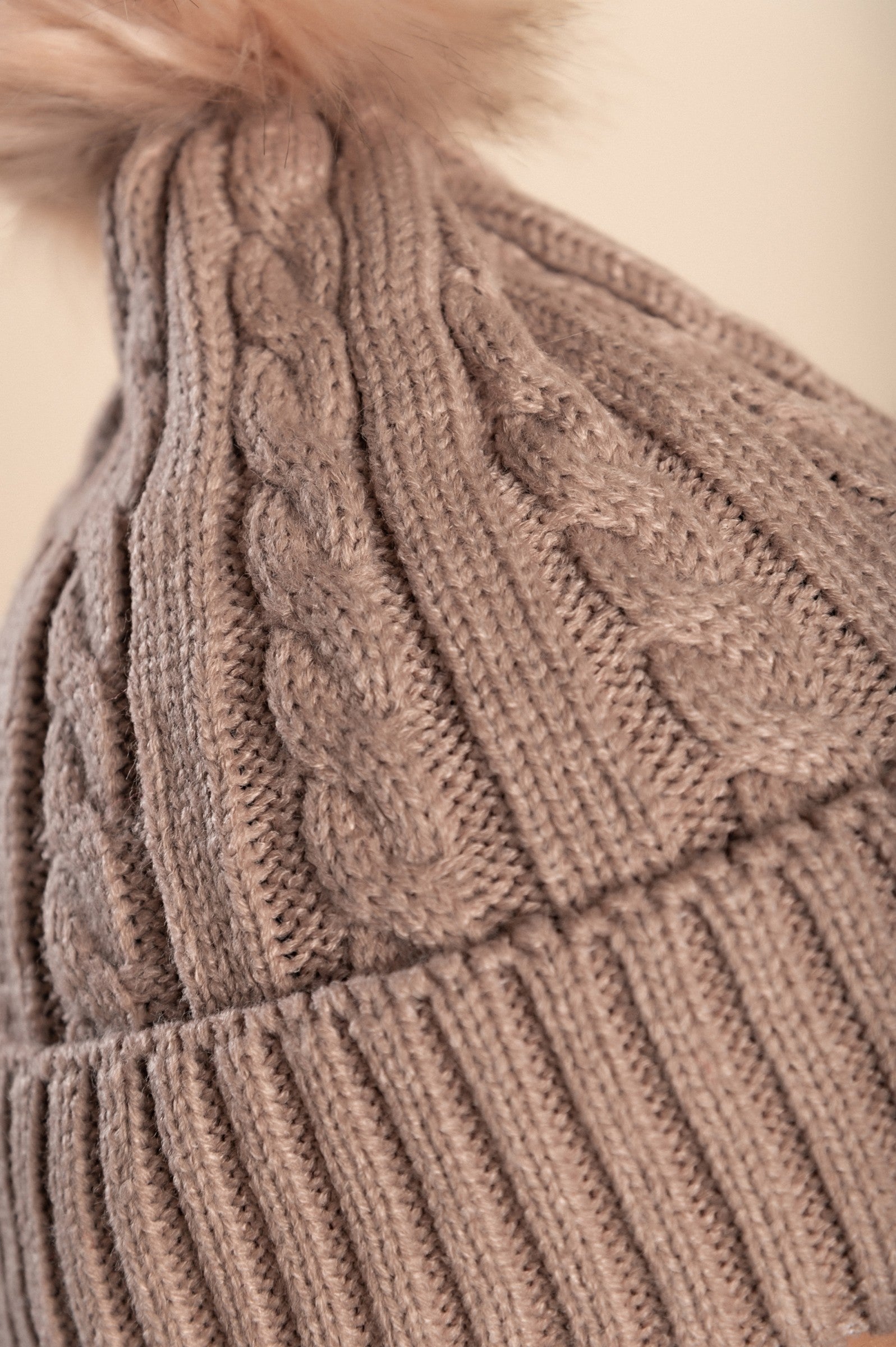 Camel knitted hat with a decorative faux fur pompom on top, showcasing a rolled edge design.