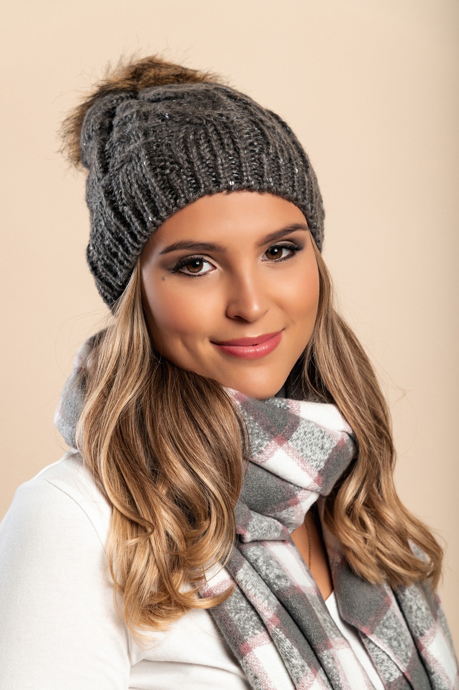 Gray knitted hat with sequins and faux fur pompom, showcasing a stylish ribbed knit design.